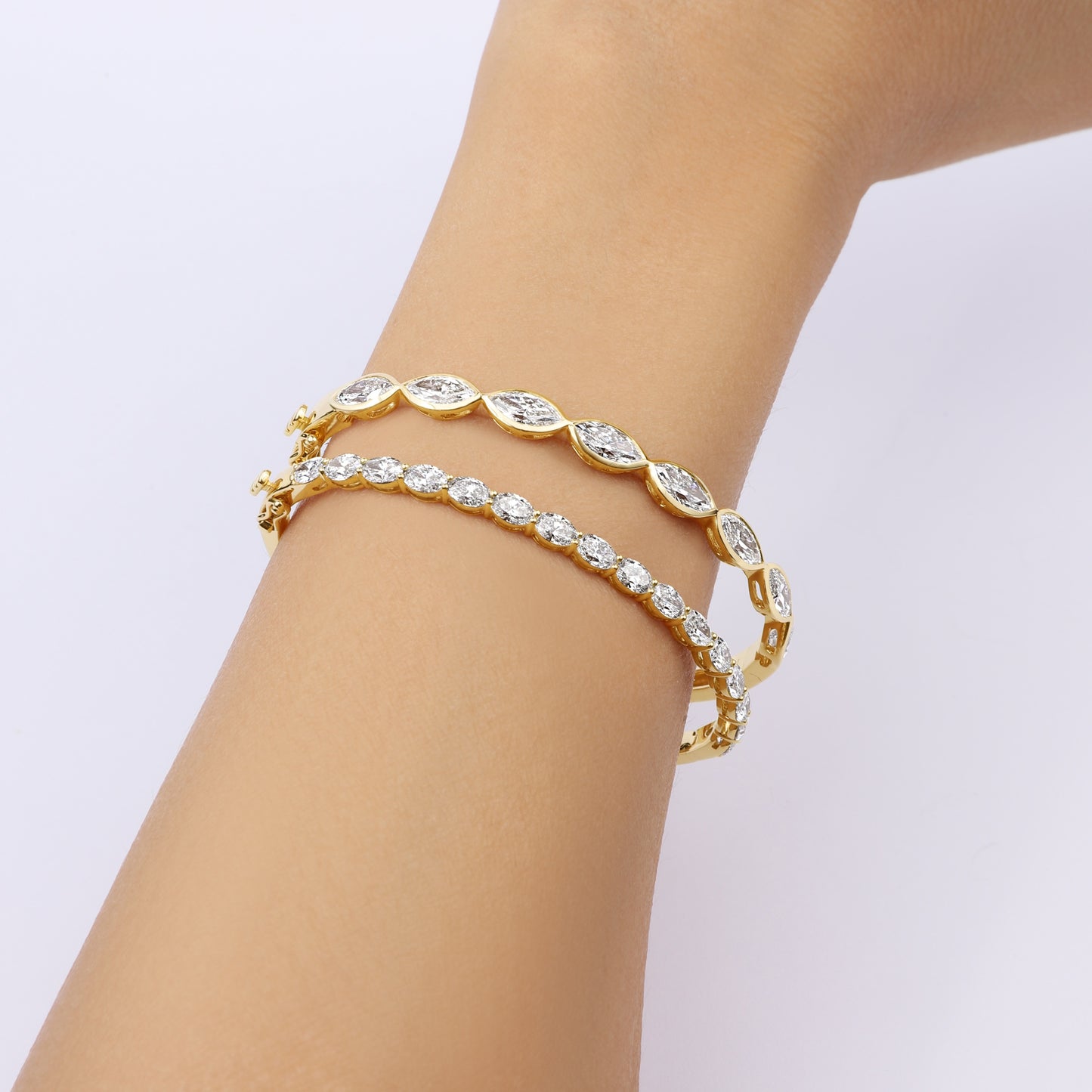 Close-up of hand wearing the Oval Bezel Set East West Tennis Bracelet with 5.5ct EF color, VS clarity lab-grown diamonds in 14K yellow gold