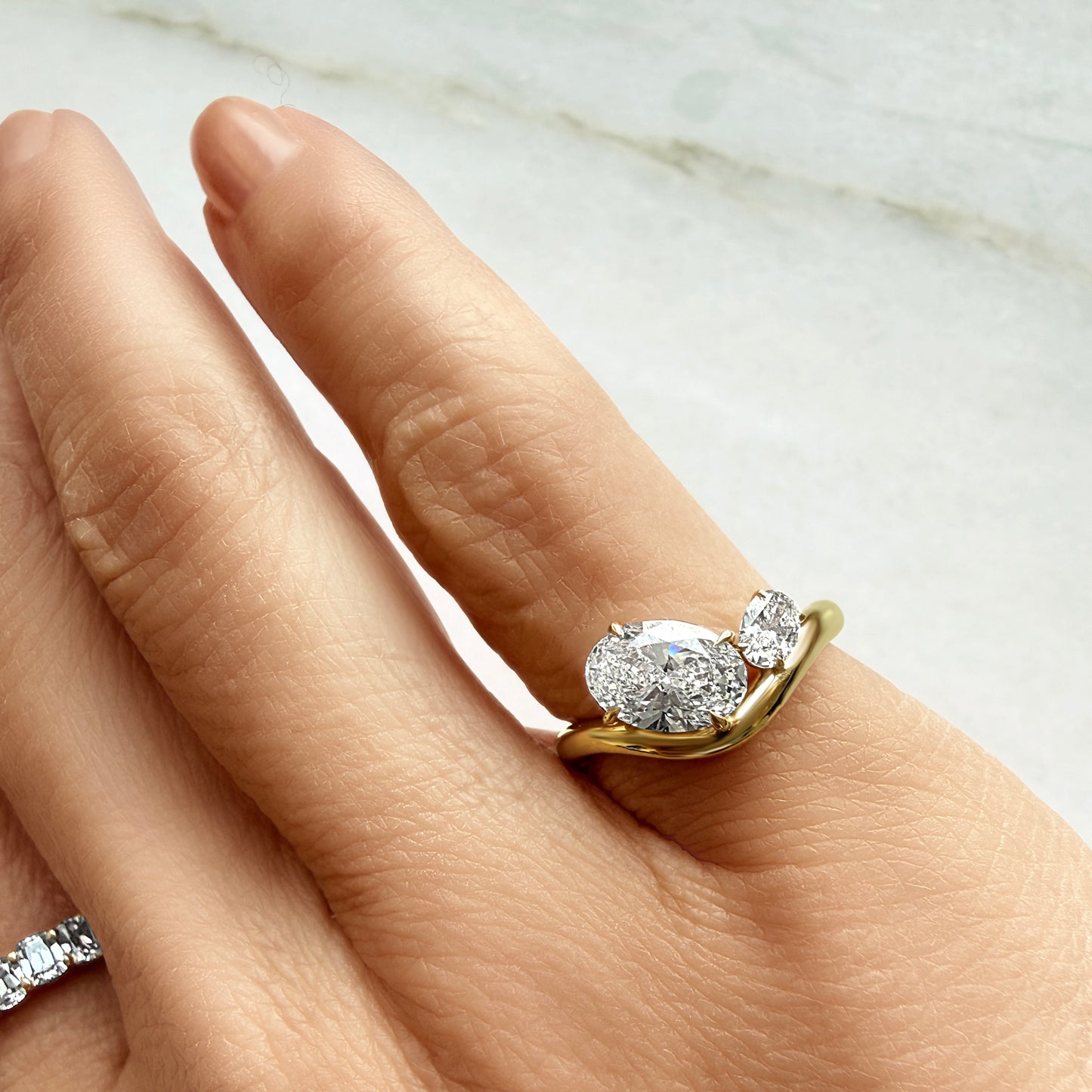Lumeniri The Lissandra Pinky Ring worn on hand, showcasing 1.25ct oval lab grown diamond in EF VS clarity, sculptural wave inspired 14K gold design, elegant modern fine jewelry styling.
