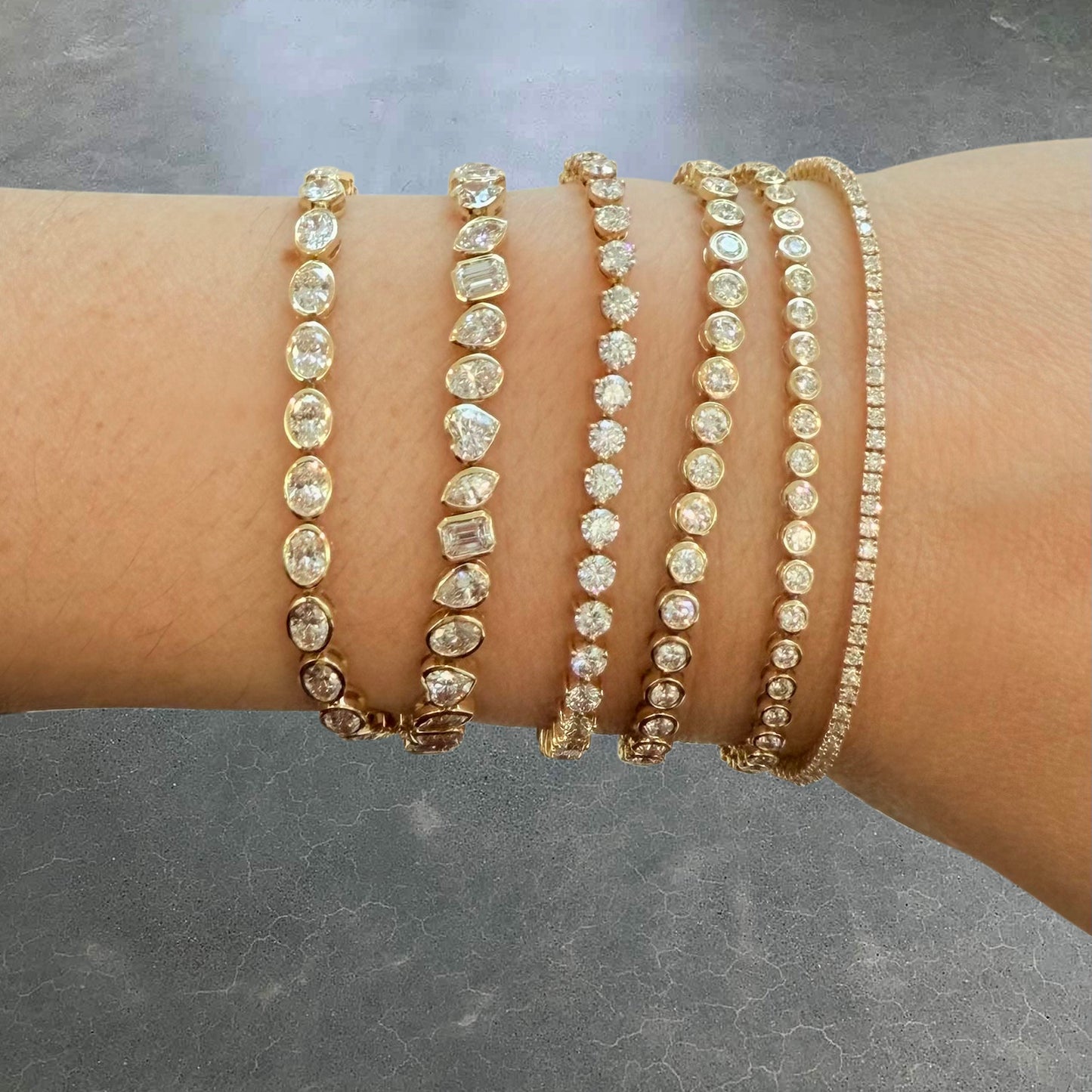 Natural light hand model shot featuring the Oval Bezel Set East West Tennis Bracelet with 5.5ct lab-grown diamonds in 14K yellow gold